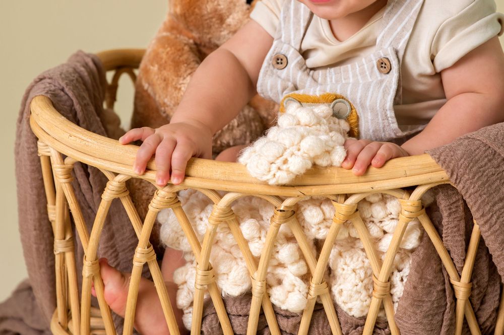 Hands weaving natural fibers into a wicker basket pattern on a wooden surface.