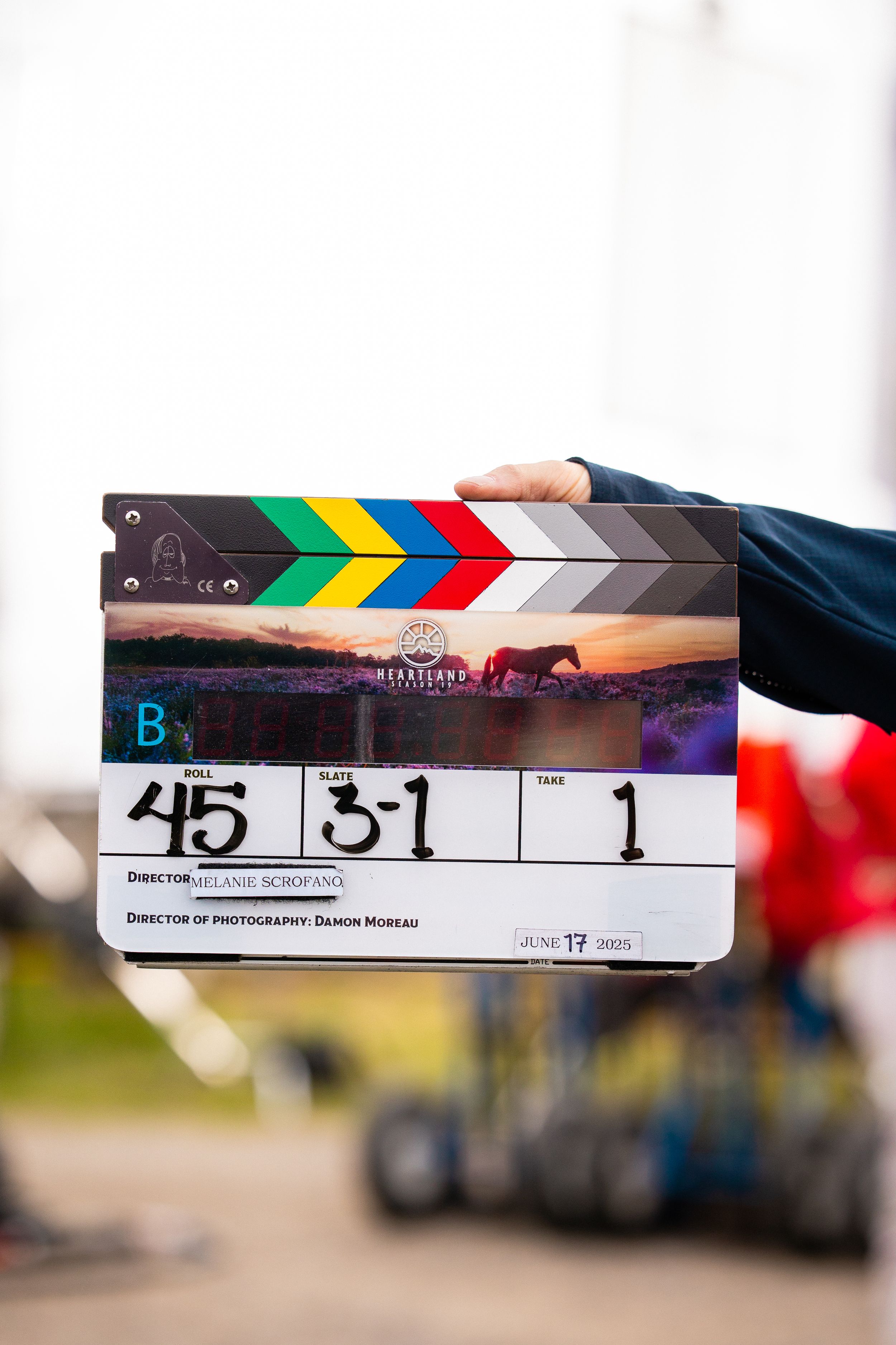 Film clapperboard showing Grassland production details held on outdoor movie set location.