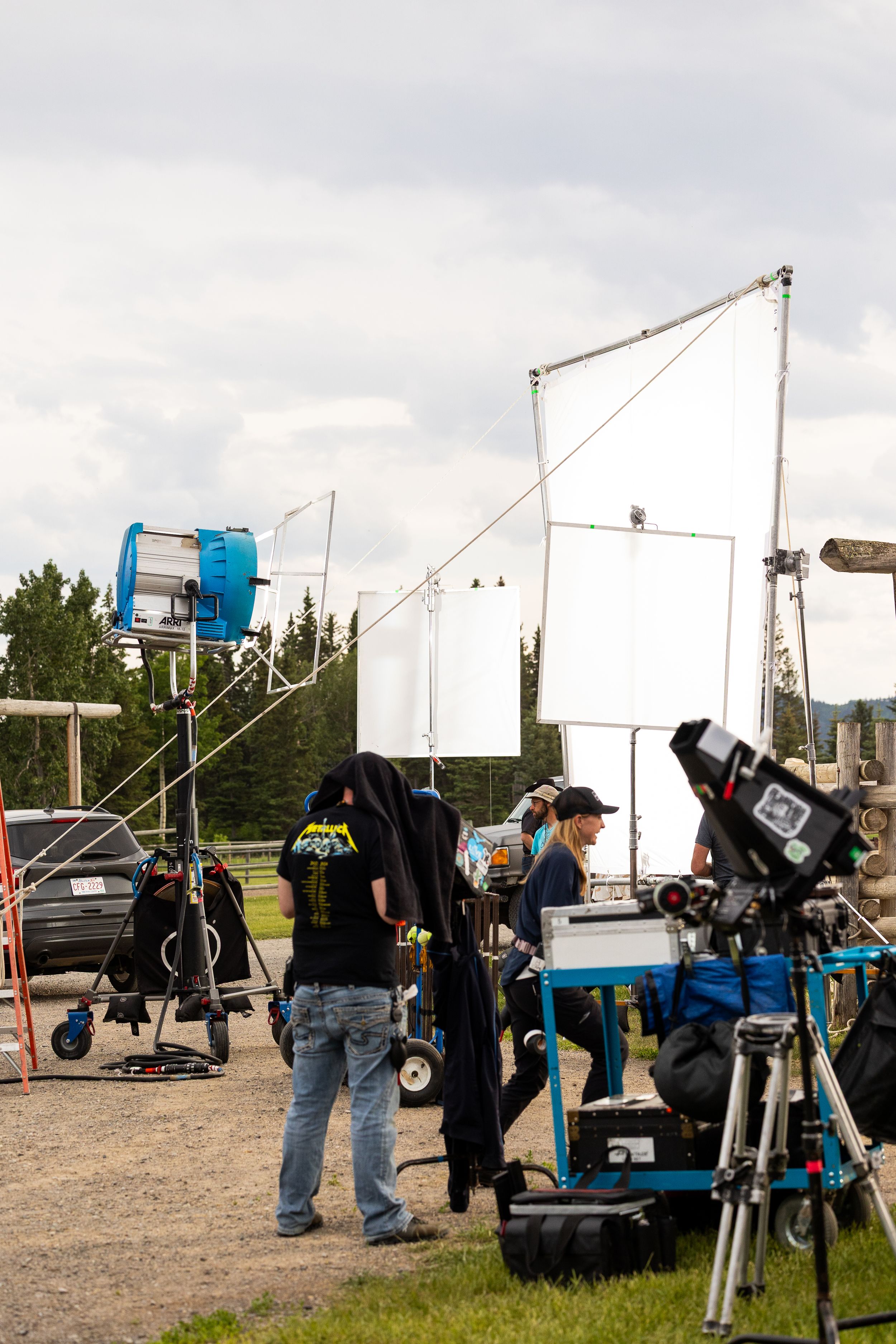 Film crew with professional lighting equipment and cameras set up on outdoor ranch location.
