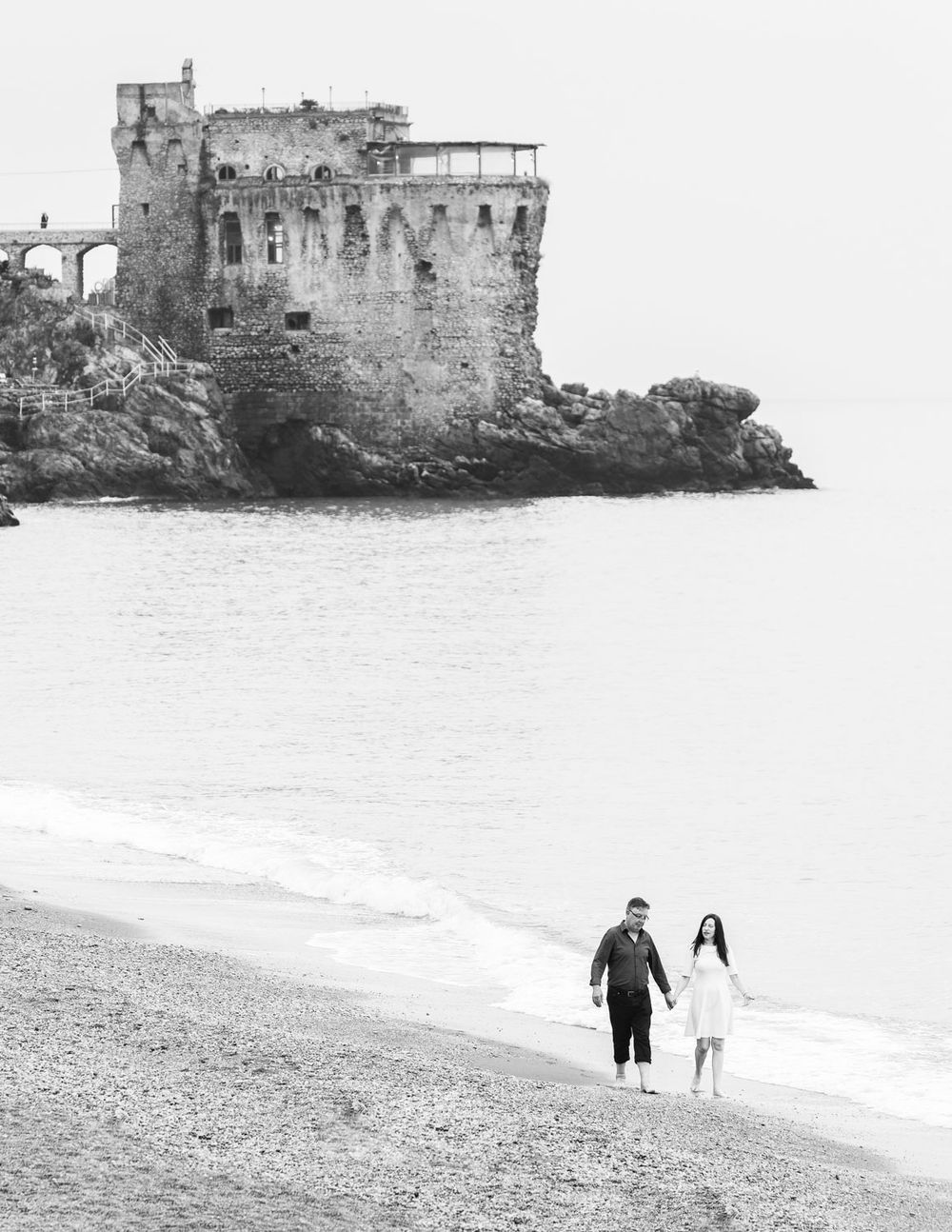 Couple enjoy paddling in sea in historic setting