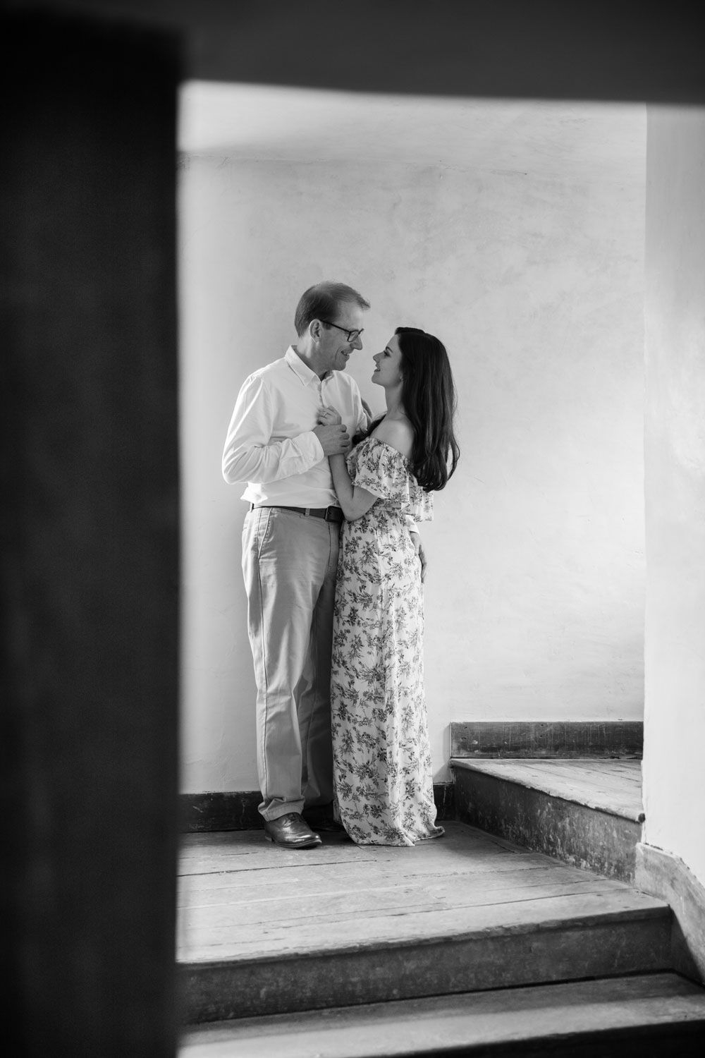 Black and white shot on couple in romantic pose on stairway of historic house