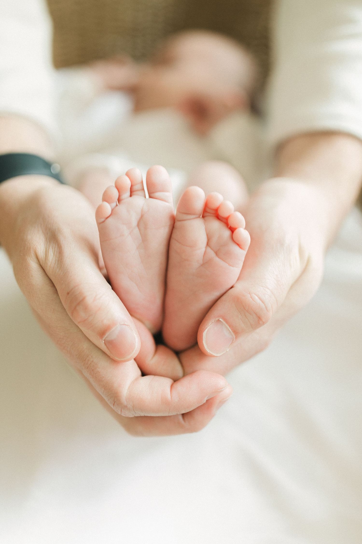 A series of soft, delicate baby feet photographs arranged in a horizontal row against a white background.