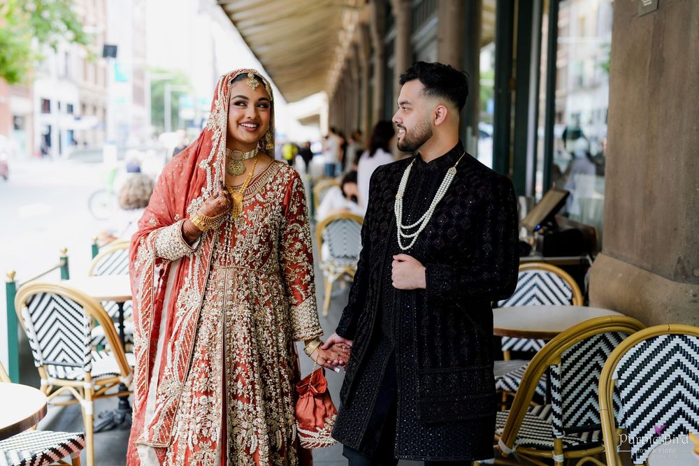 A couple in traditional wedding attire shares intimate moments at a restaurant with geometric patterned seating.