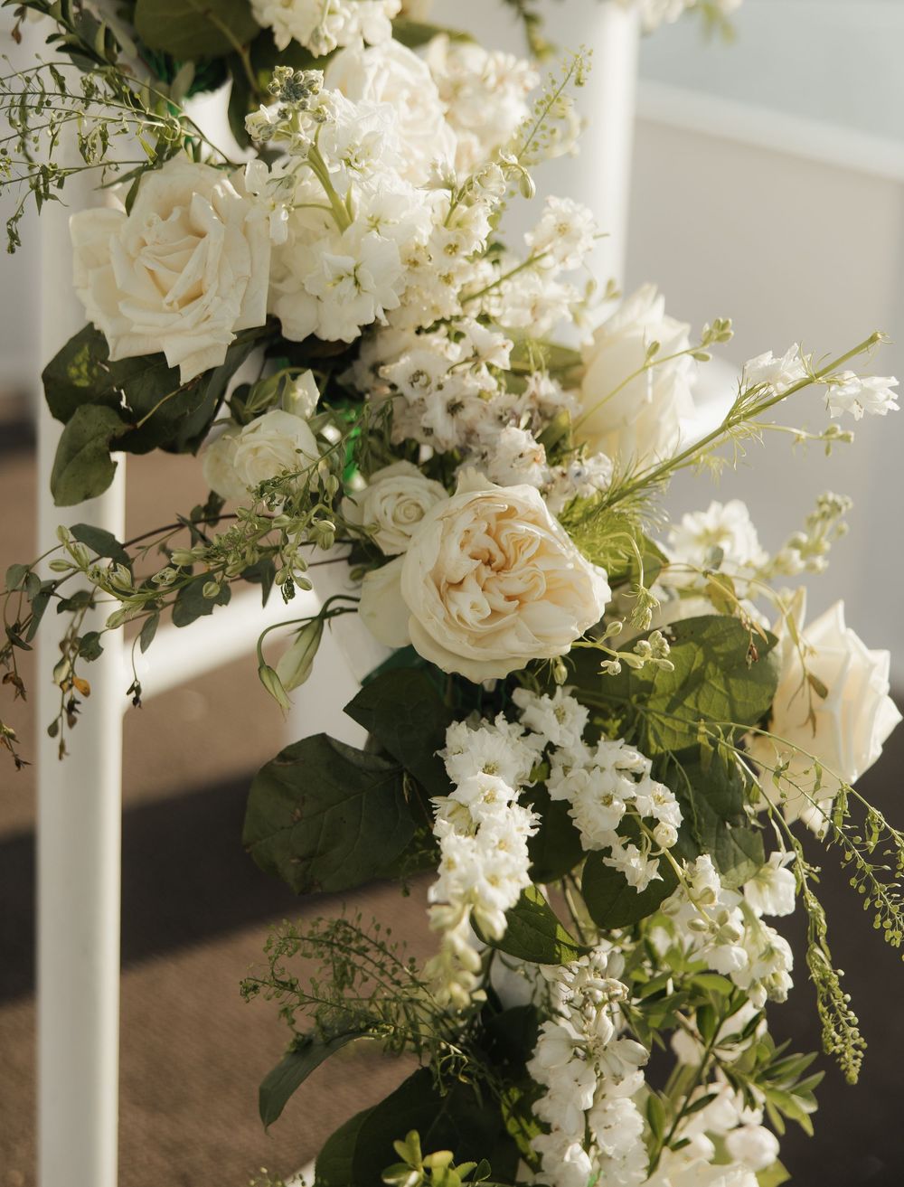 Elegant white floral arrangements with roses and greenery decorating a wedding venue.
