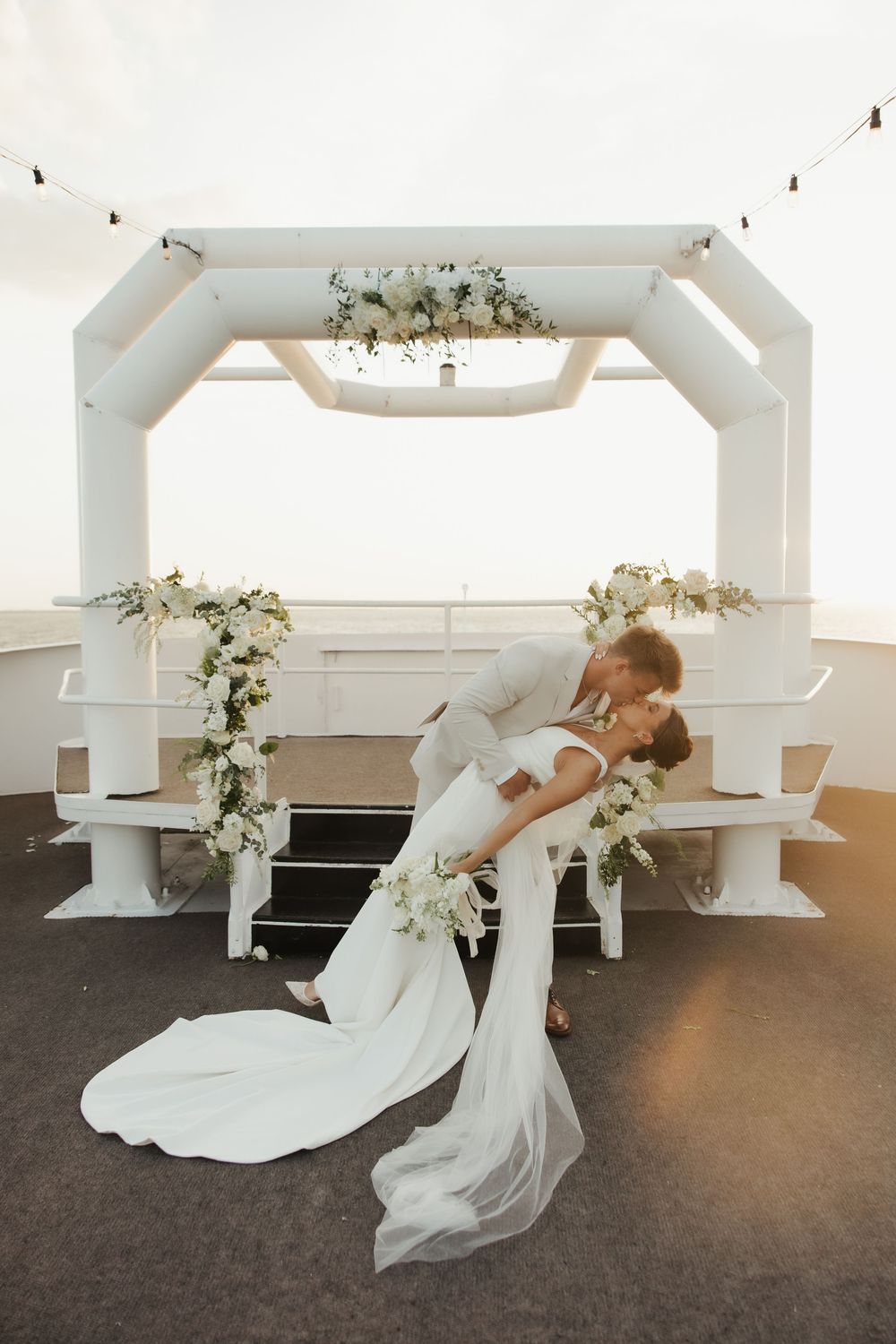 Dancing couple twirls gracefully in a white room with floral decorations.