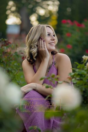 Rose Garden Julia Davis Park Boise Idaho Senior photo focus through the flowers girl smiling profile looking to camera right