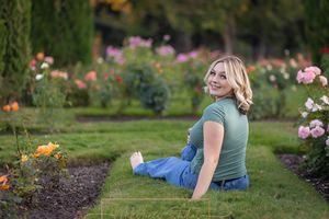 Rose Garden Julia Davis Park Boise Idaho Senior photo girl wearing green t-shirt and jean in rose garden looking over shoulder