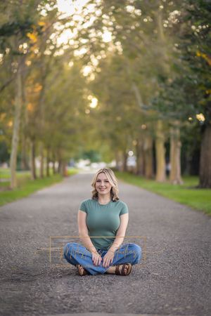 Rose Garden Julia Davis Park Boise Idaho Senior photo girl wearing green t-shirt and jeans sitting in tree lined path
