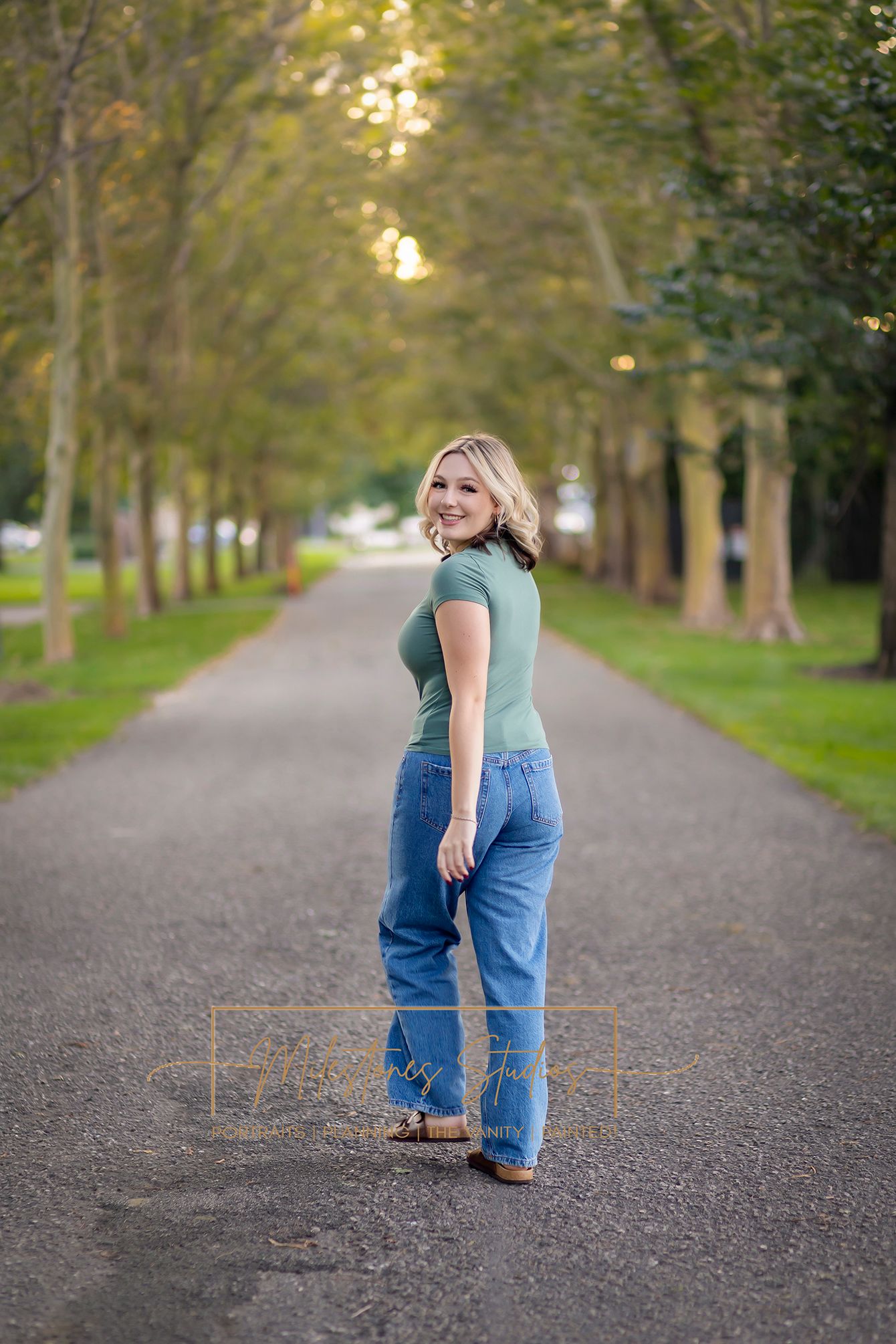 Rose Garden Julia Davis Park Boise Idaho Senior photo girl wearing green t-shirt and jeans walking away with treelined path