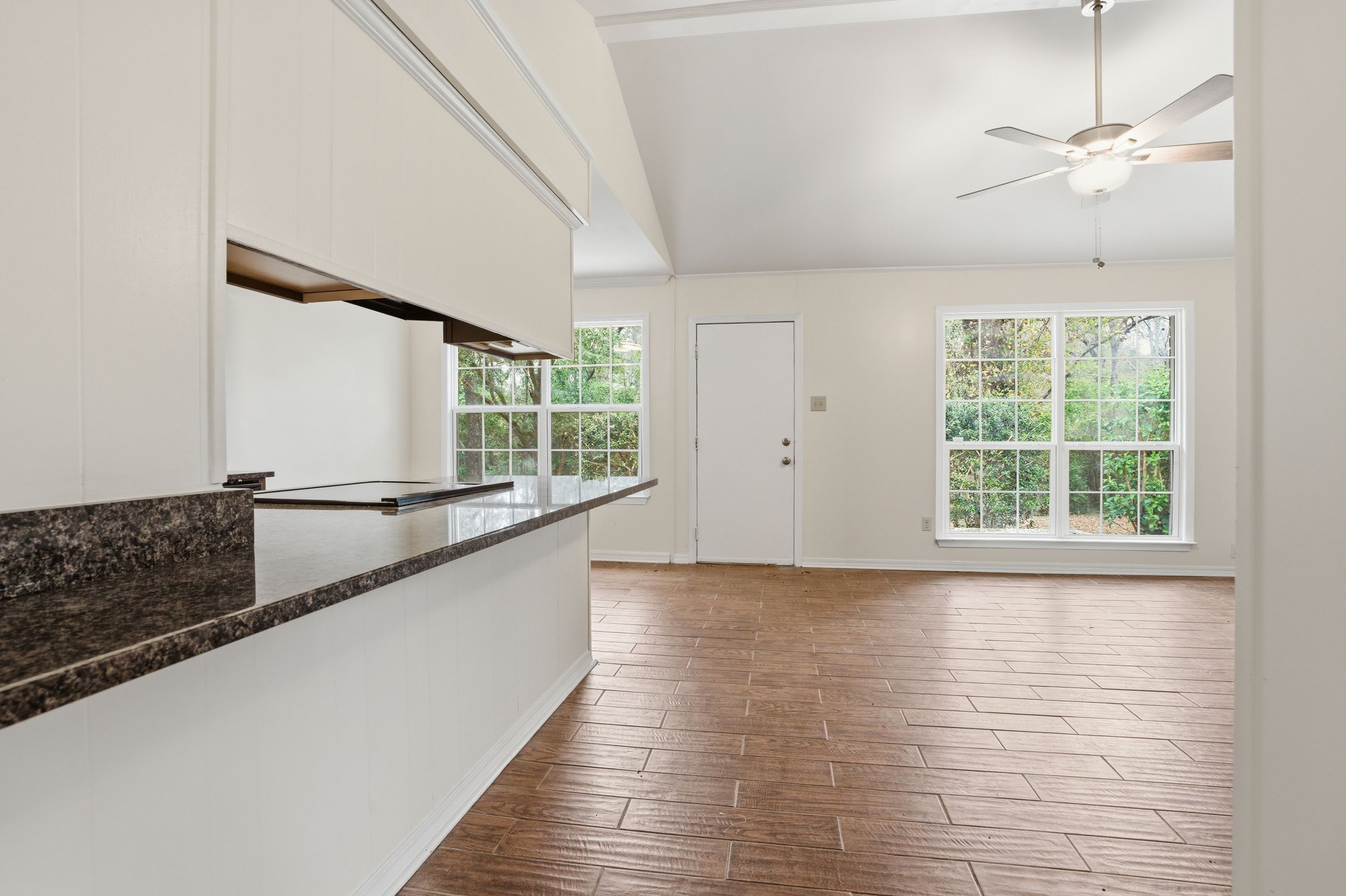Modern open concept living space with hardwood floors and large windows providing natural light.