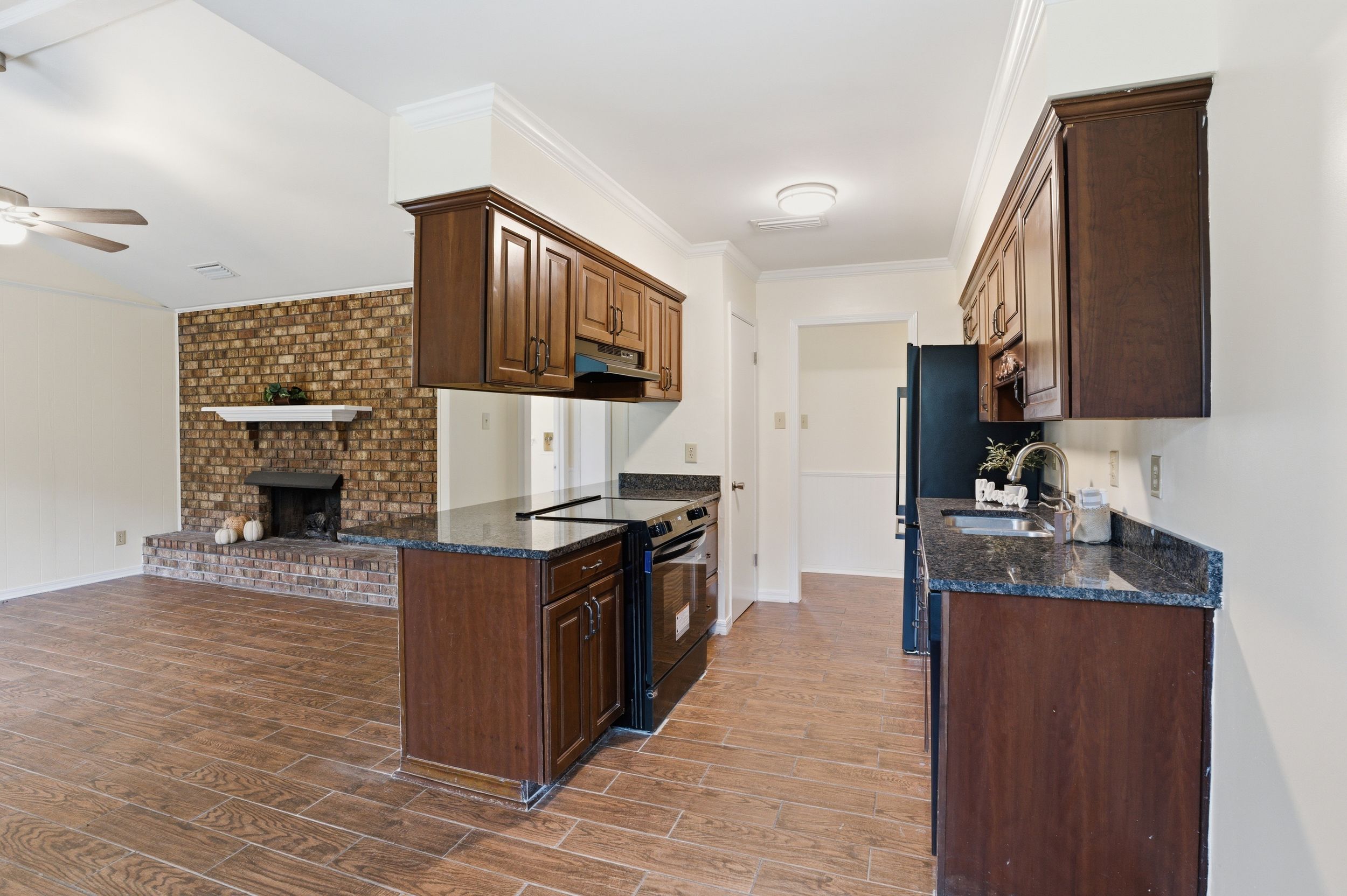 Modern kitchen interior with brown cabinets, granite countertops, and tile flooring in an open concept layout.