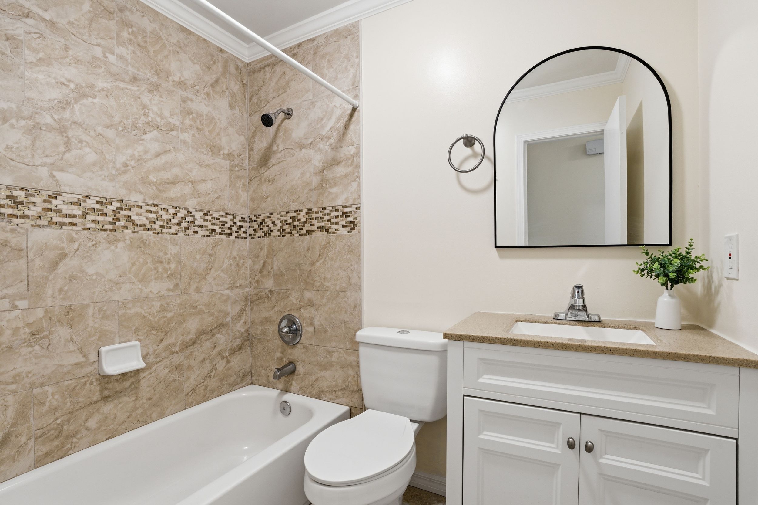Elegant bathroom with beige marble tile, glass shower enclosure, and modern vanity fixtures.