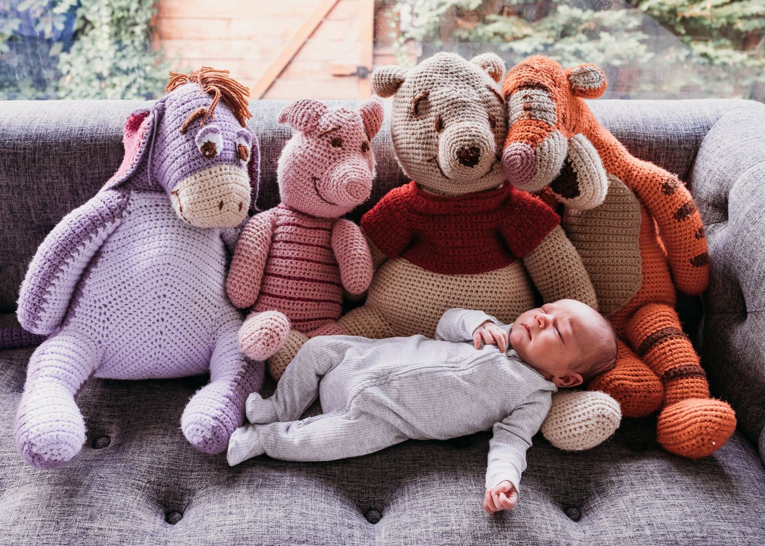 A collection of stuffed plush toys including bears, elephants, and tigers arranged in a row on a couch or sofa.