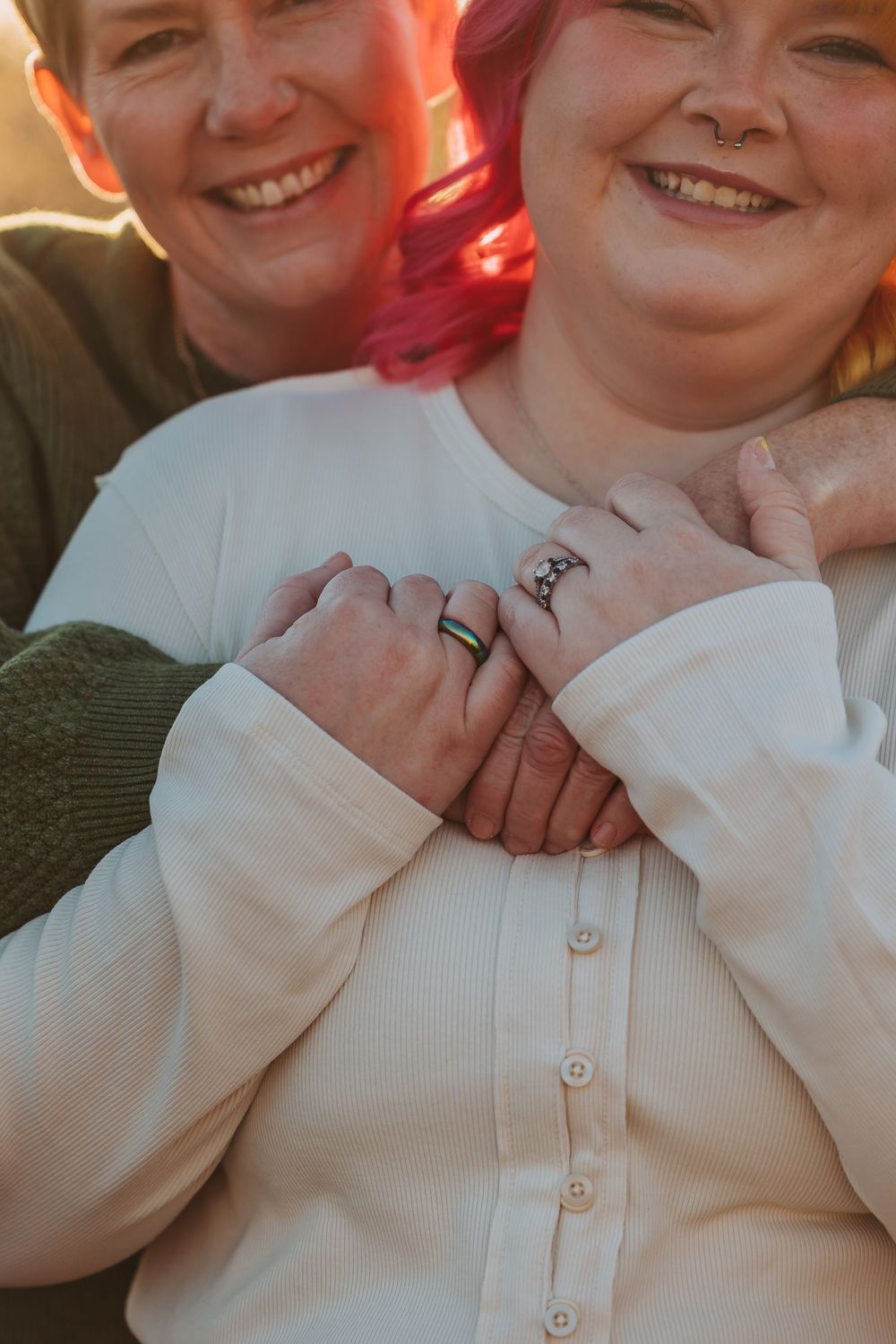 Two people wearing casual attire share a close moment outdoors at sunset.
