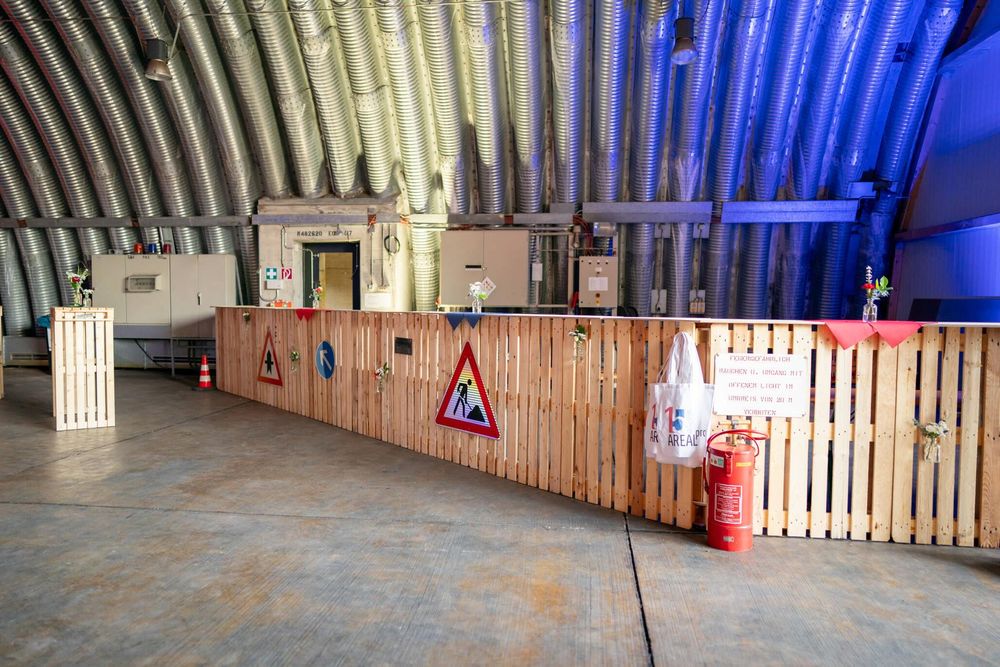 Large industrial space with wooden pallet walls lit by dramatic blue and white lighting effects.