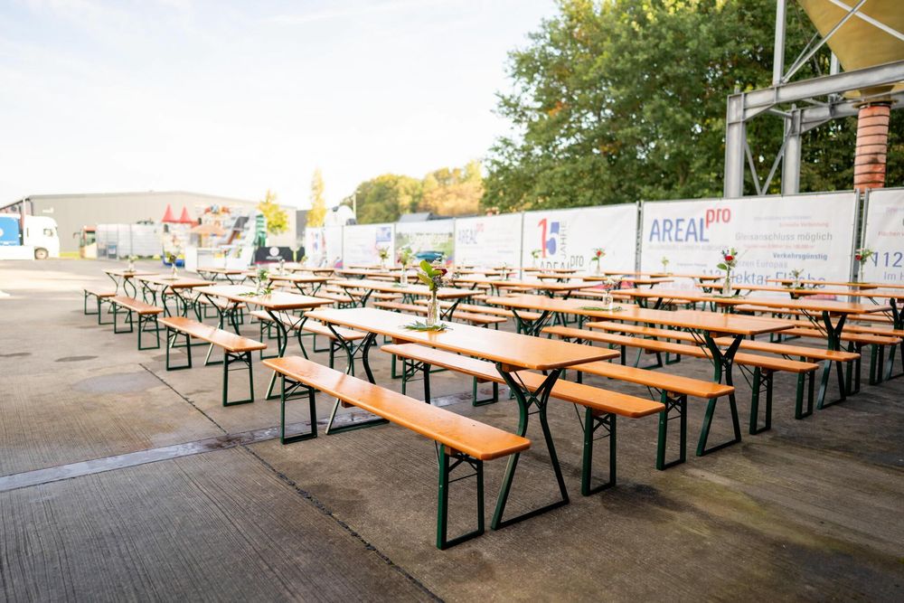 Long rows of empty wooden picnic tables and benches arranged under a covered outdoor dining area.