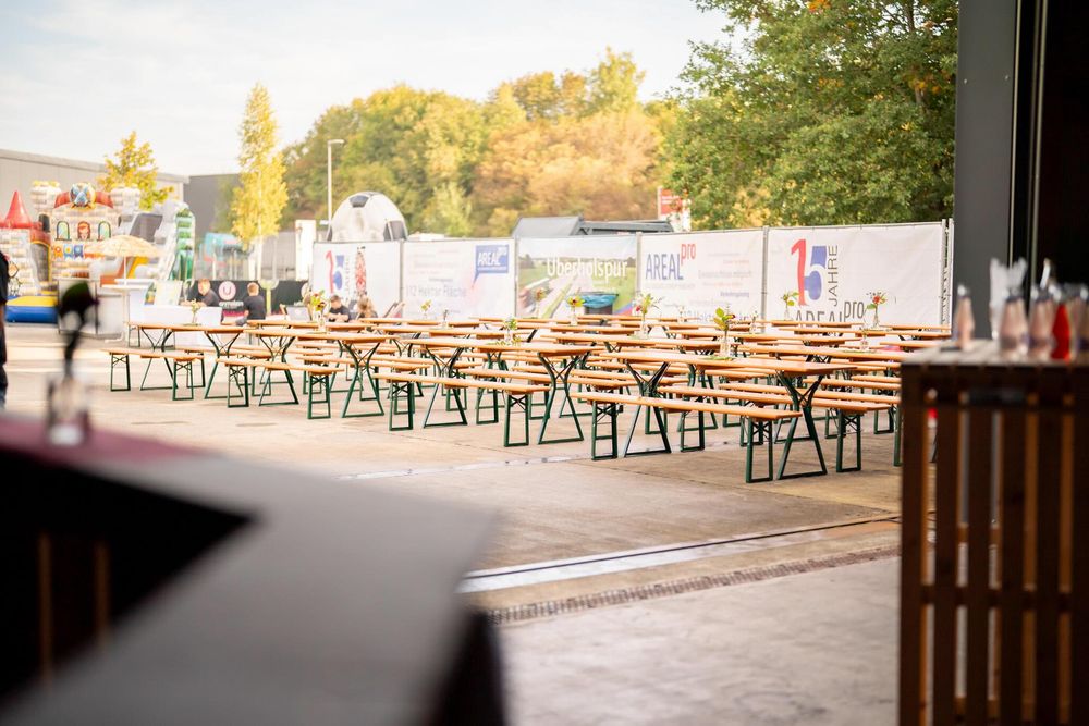 Outdoor seating area with wooden picnic tables arranged in rows on a sunny day.