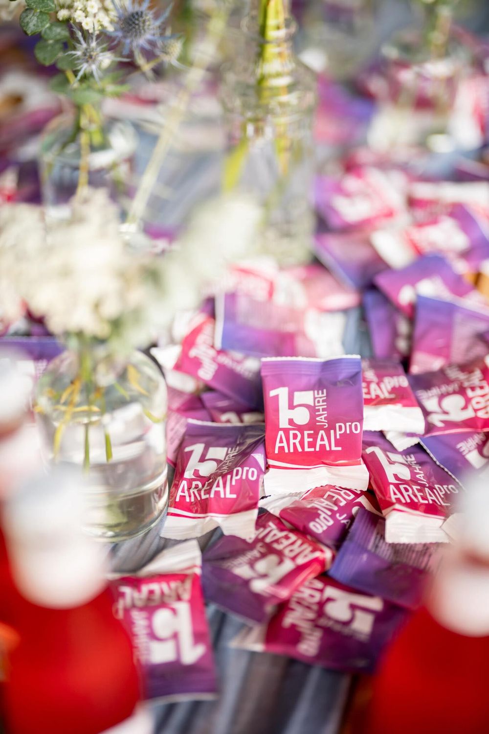 Pink Areal Pro drink packets scattered on a reflective surface with decorative holiday elements in soft focus.