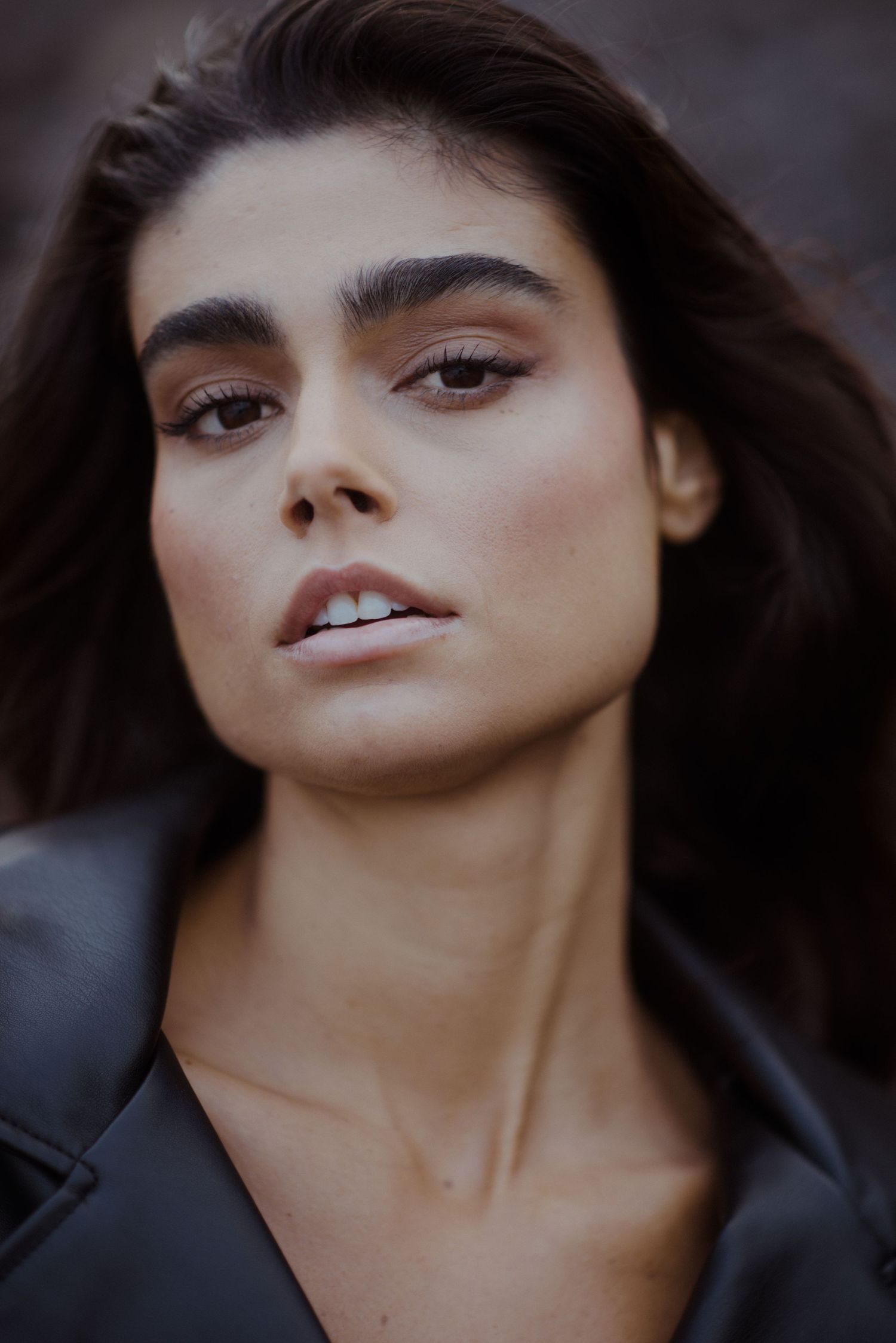 Dramatic close-up portrait with dark hair and expressive features in moody lighting.