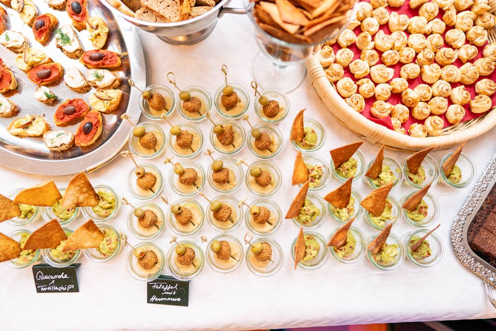 Assorted appetizers and finger foods arranged on white plates including pastries, snacks, and hors d'oeuvres.