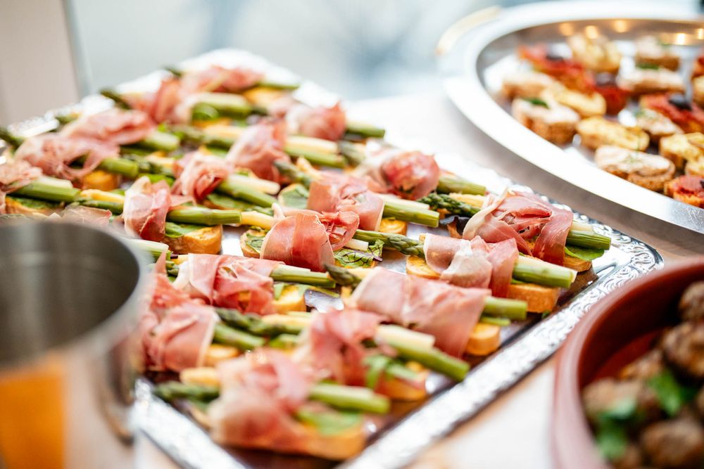 Prosciutto-wrapped asparagus appetizers arranged on serving platters for an elegant party spread.