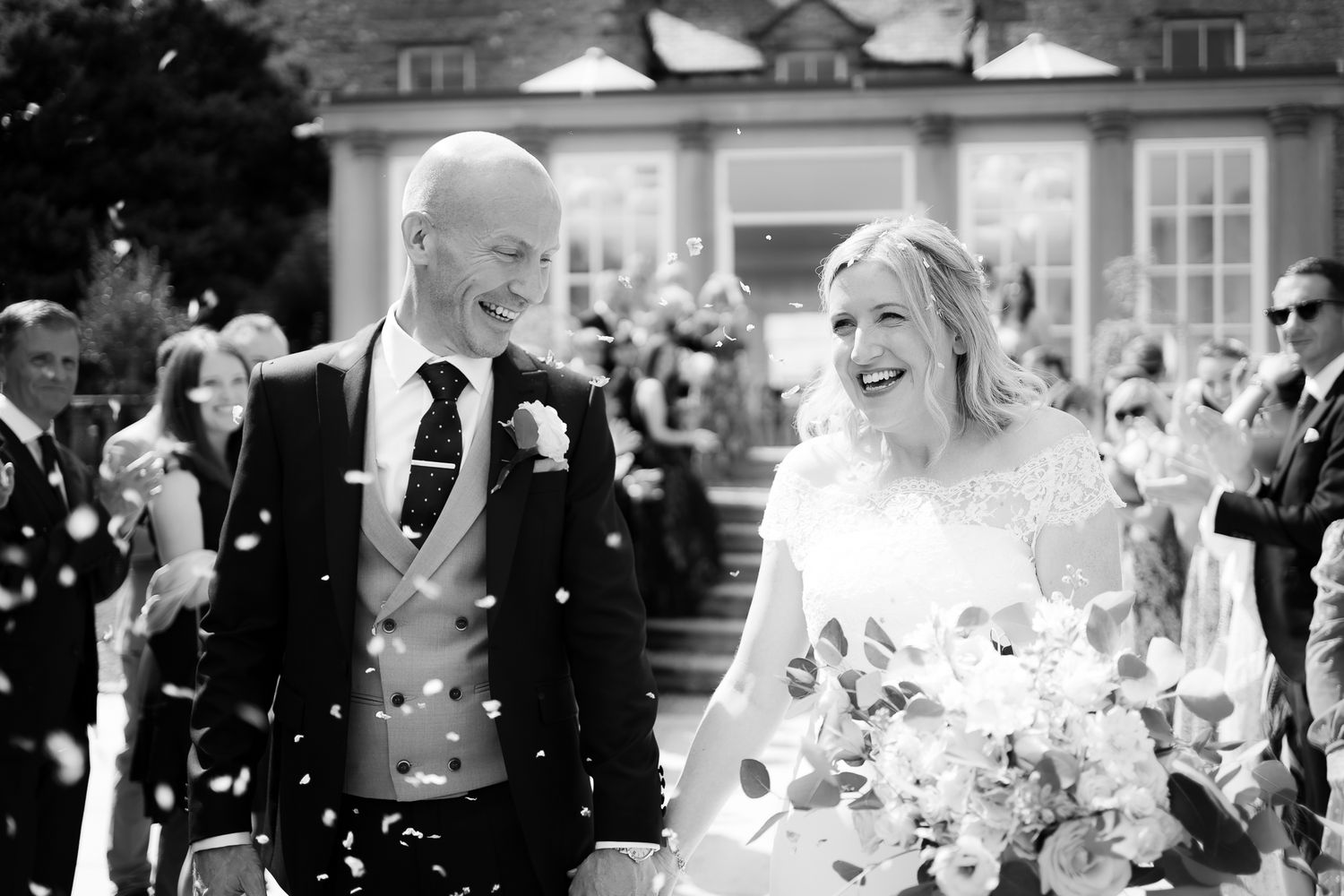 Wedding celebration with confetti flying through the air in black and white. Woodhill Hall.
