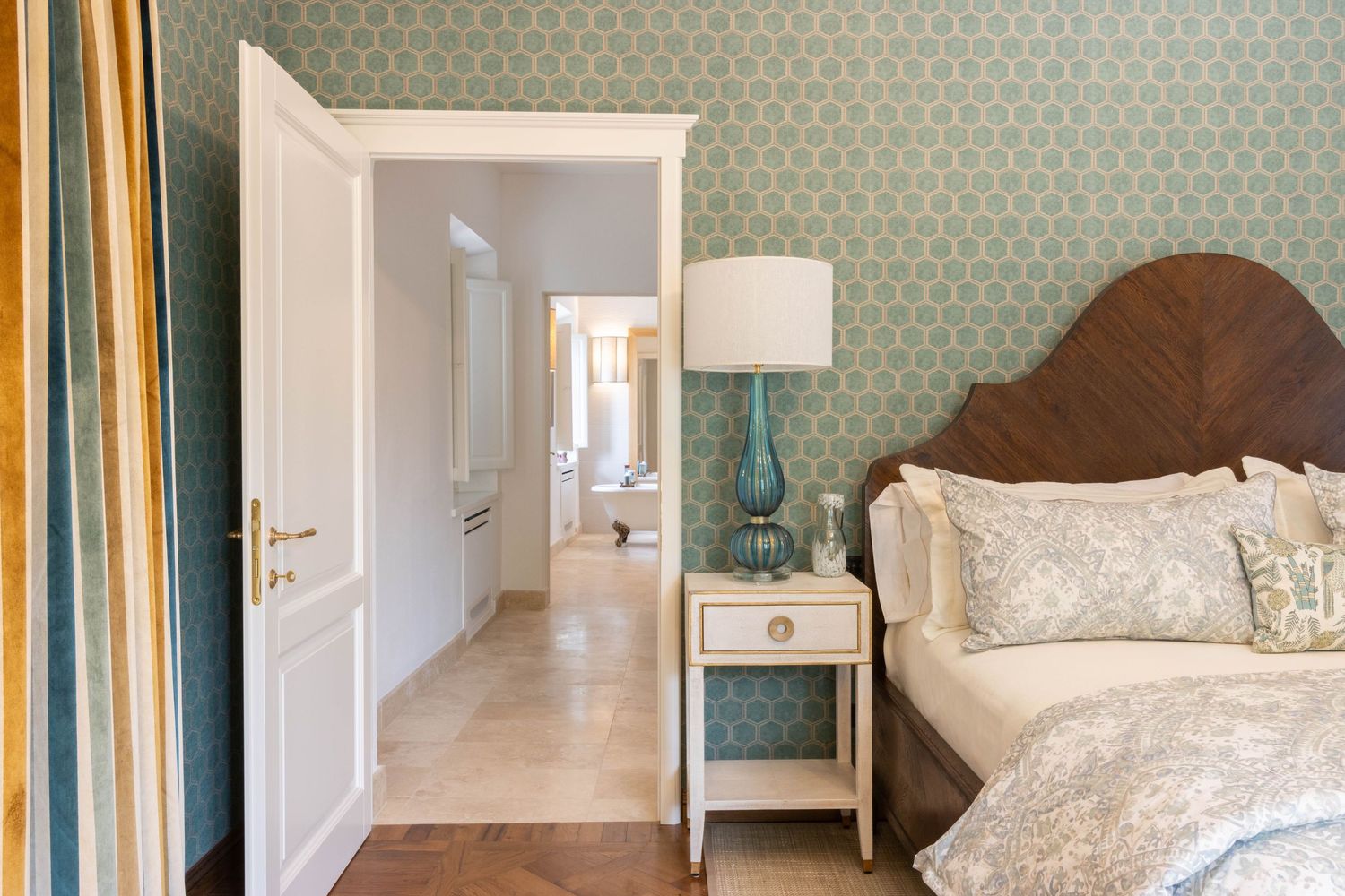 Tuscany Italy real estate photographer. A luxurious bedroom features soft blue patterned wallpaper, elegant white bedding.