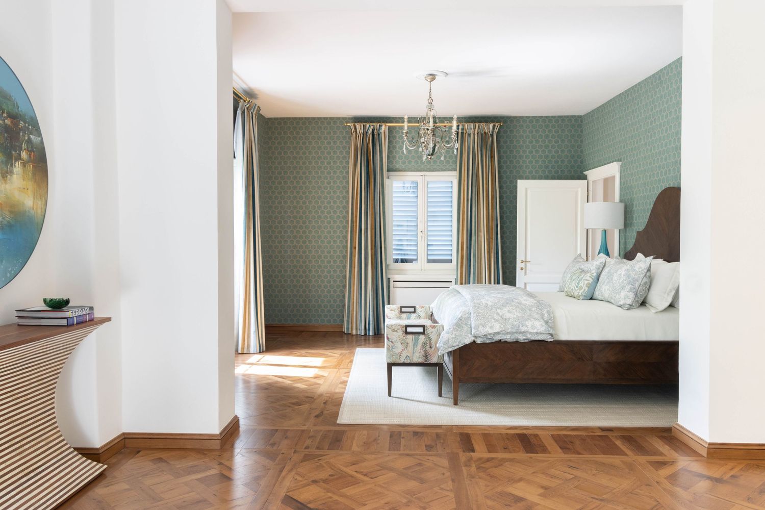 Luxury commercial property photographer in Tuscany, Italy. Elegant bedroom with sage green walls, parquet flooring, and white bedding.