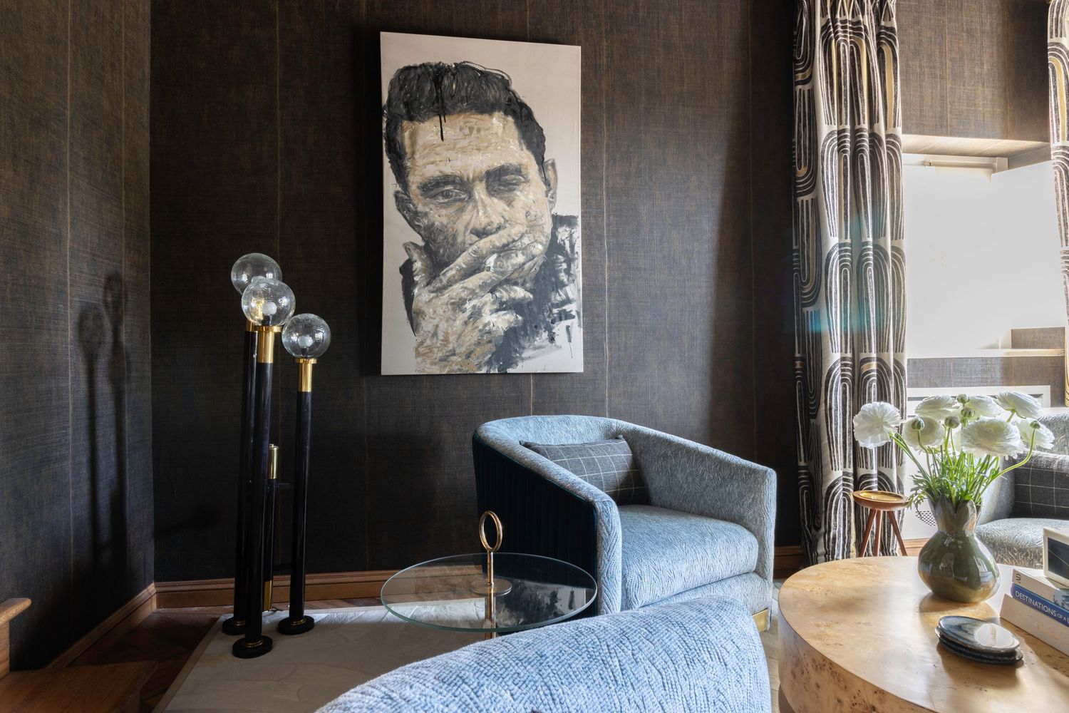 Modern apartment interior with dark walls features a sleek sectional sofa and large windows offering natural light.