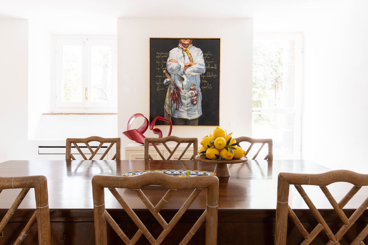 Luxury commercial property photographer in Chianti, Italy. Bright dining room with wooden chairs and white walls featuring artwork.