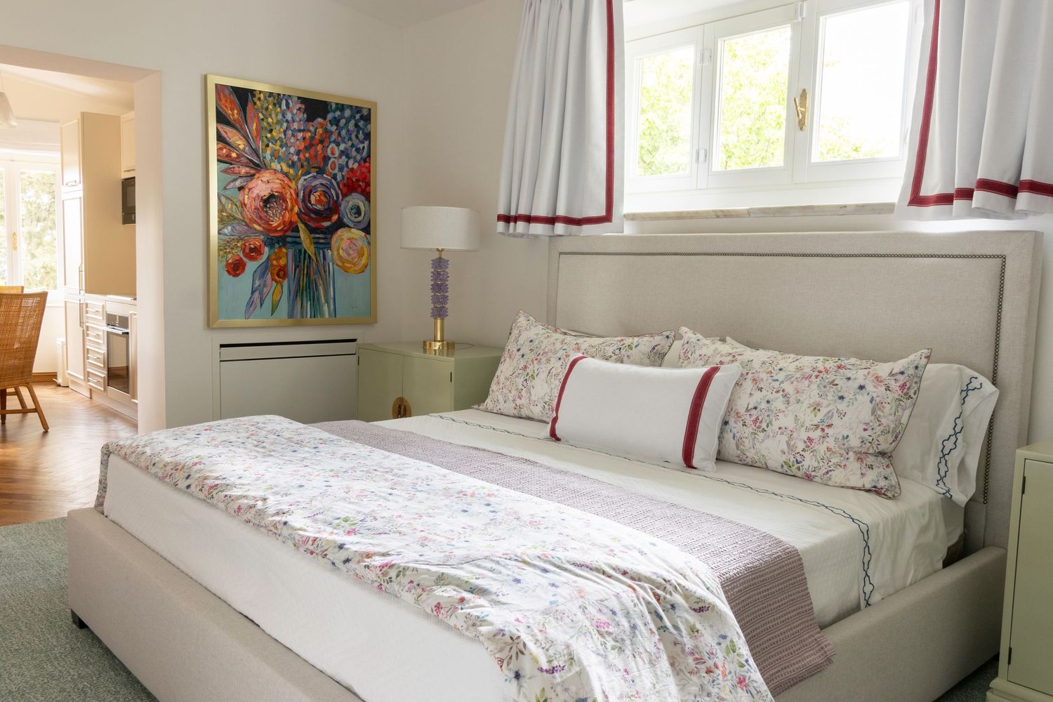 Tuscany Italy property photographer. Bright bedroom with upholstered gray headboard, floral bedding.