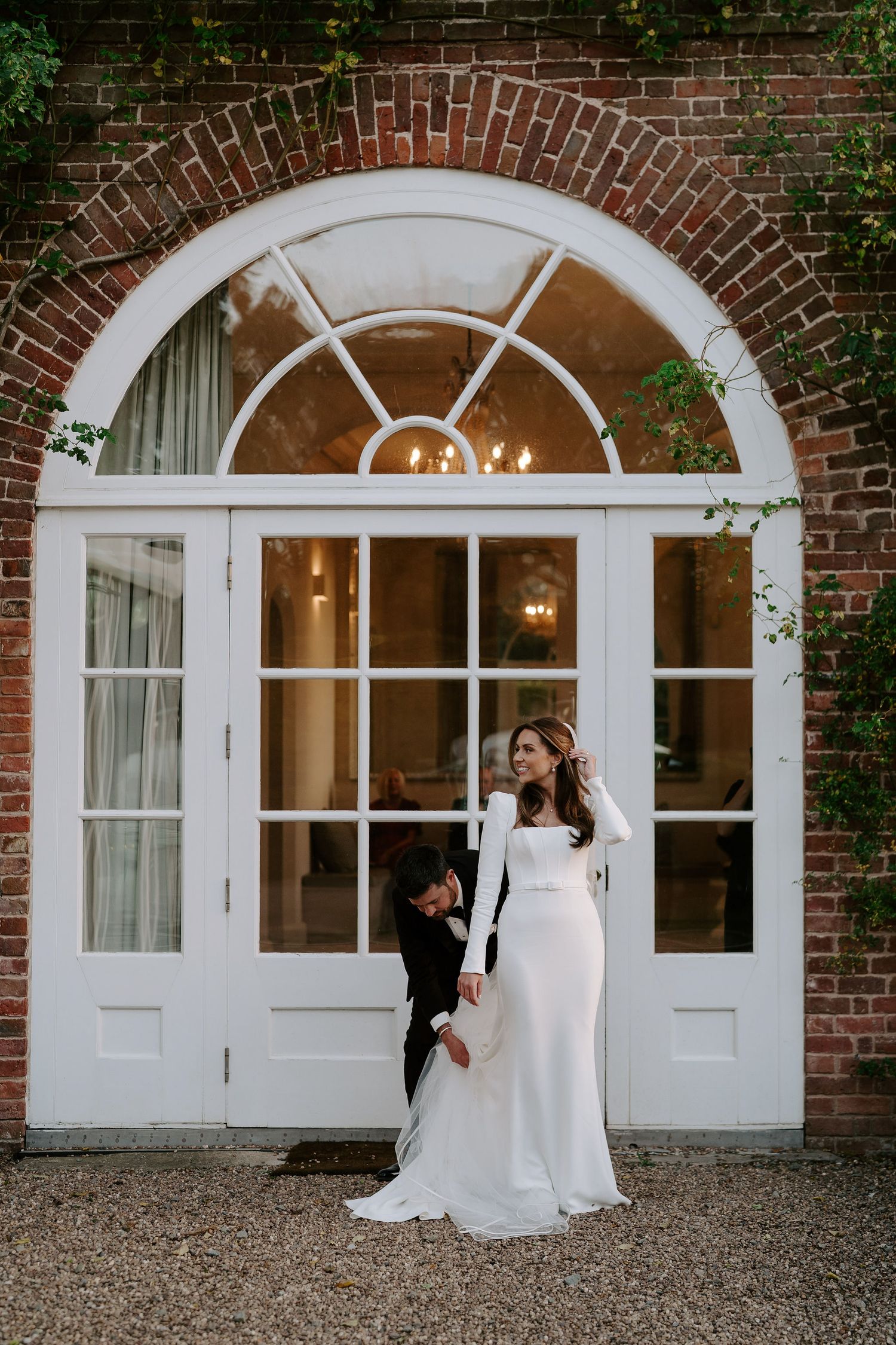groom helping bride with her wedding dress outside Iscoyd park