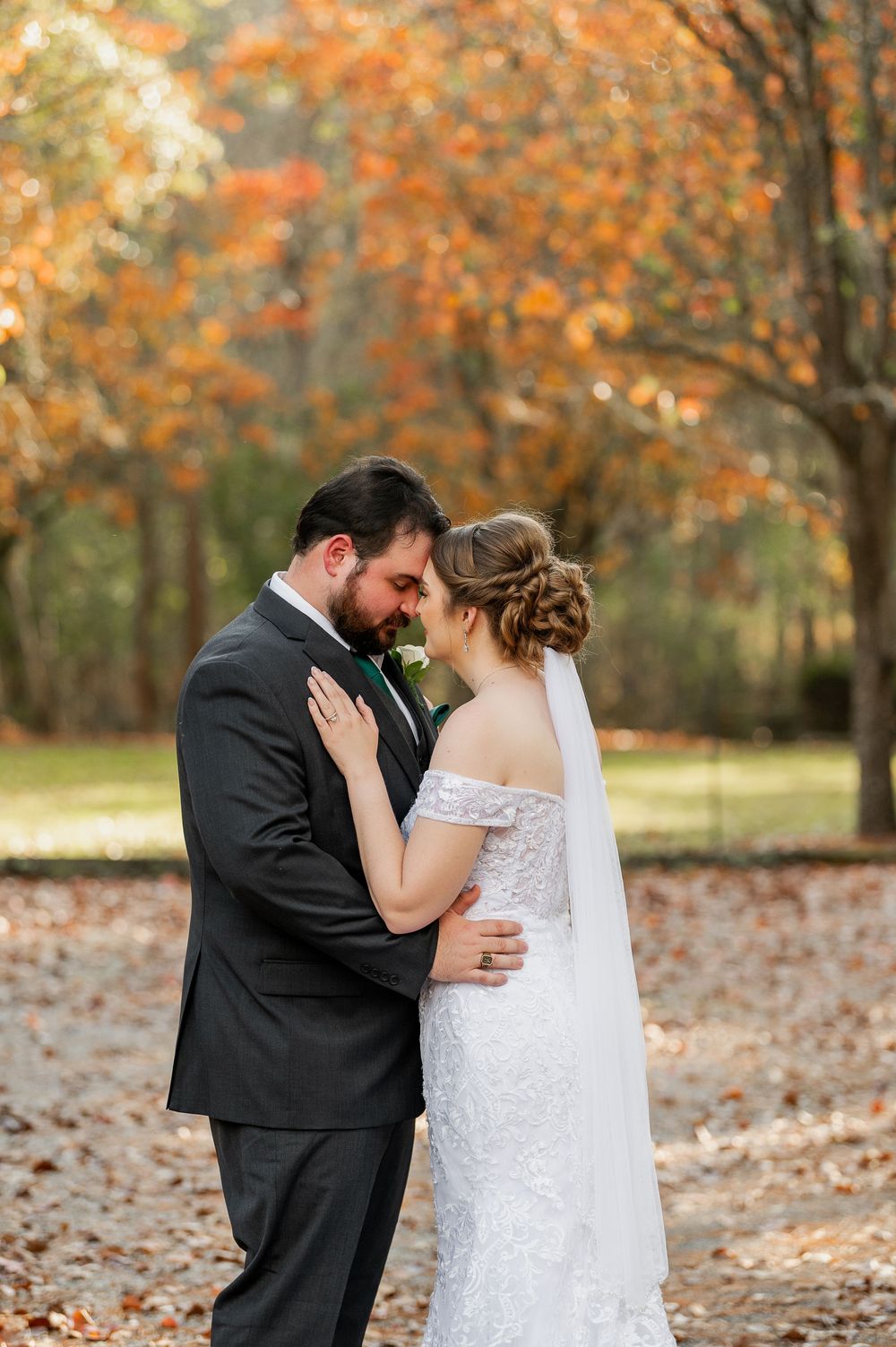 Wedding couple shares intimate moments on fallen autumn leaves in an outdoor setting.