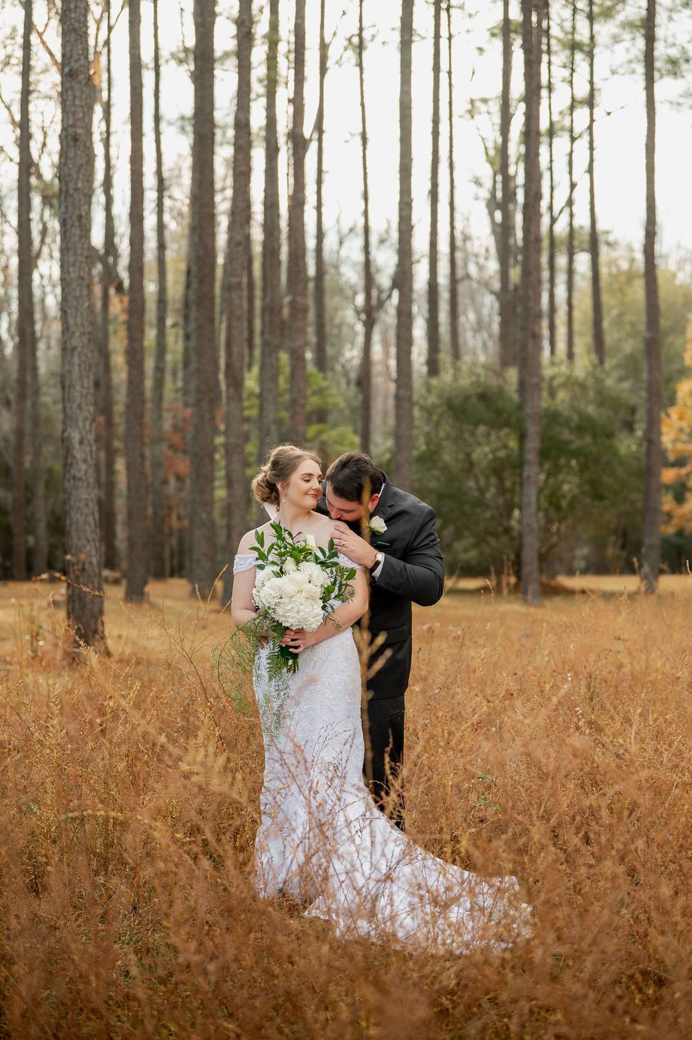 Wedding portraits in a pine forest with tall grass and warm fall colors.