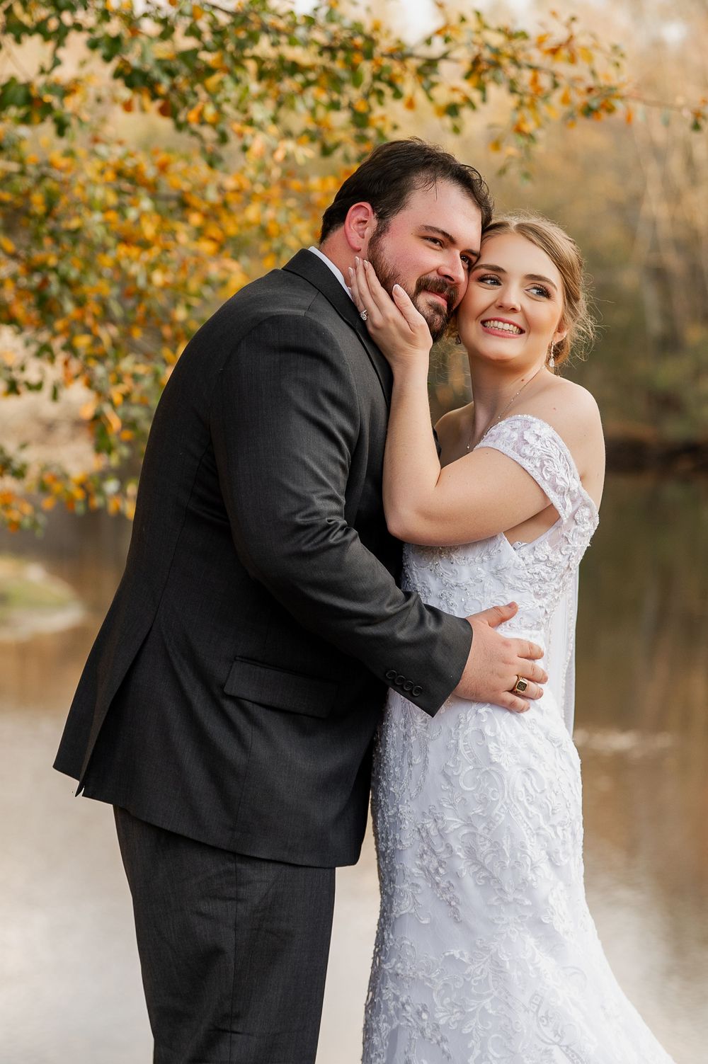 Candid wedding moments captured by a lake with fall foliage in the background.