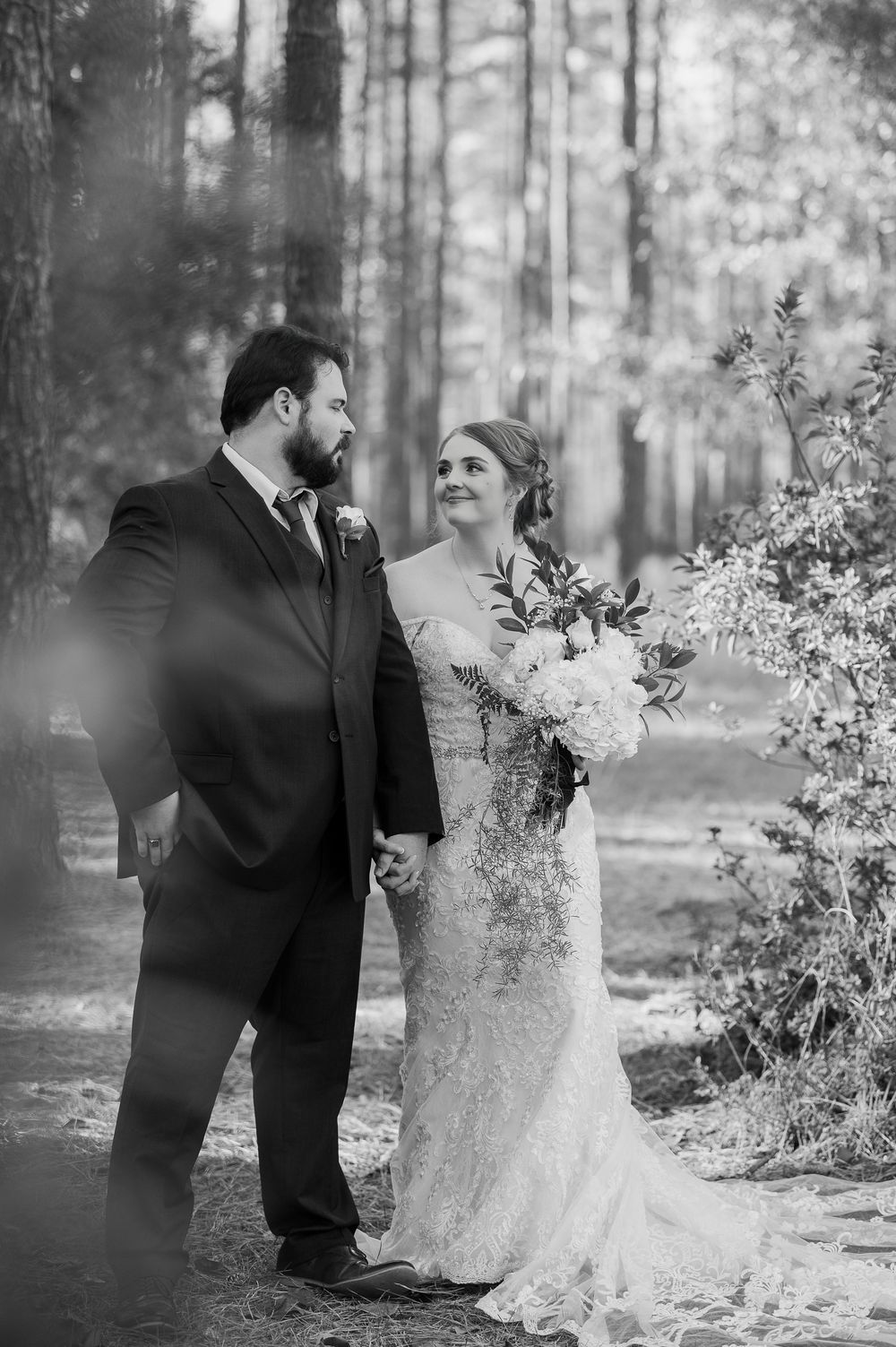 Black and white wedding portraits showing a couple in formal attire against a wooded backdrop.