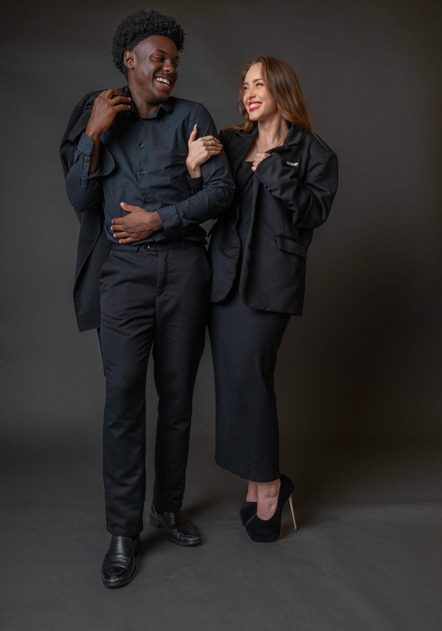 Professional branding portrait photography of a well-dressed couple in black attire, posed confidently together in a clean studio setting