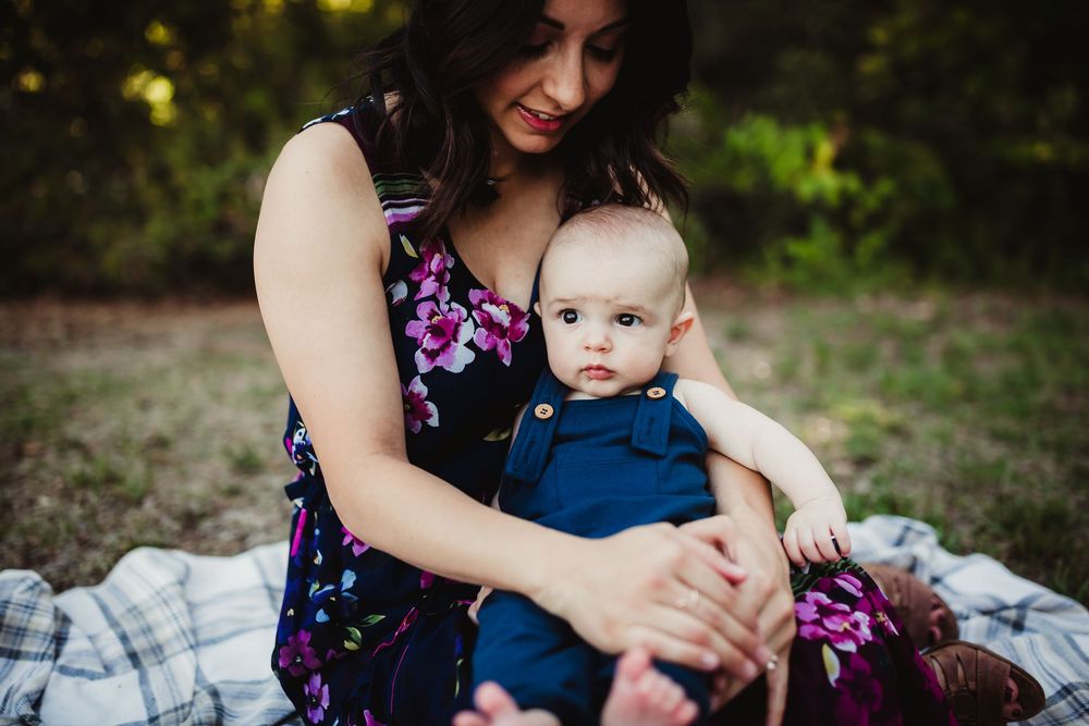 A tender moment between parent and child sitting on a blanket outdoors during a photo session.