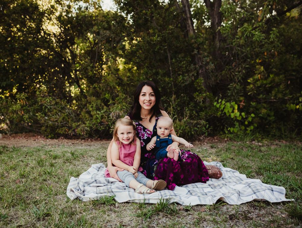 Family lifestyle photography session shows intimate moments between parent and child on a picnic blanket outdoors.