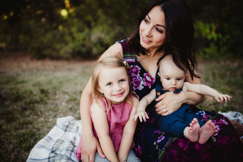 Natural light family photos capture candid moments between mother and children during an outdoor session.