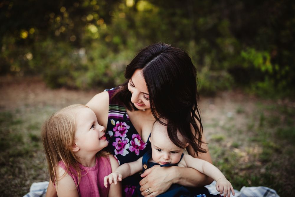 A tender moment is captured between family members on a blanket during an outdoor portrait session.