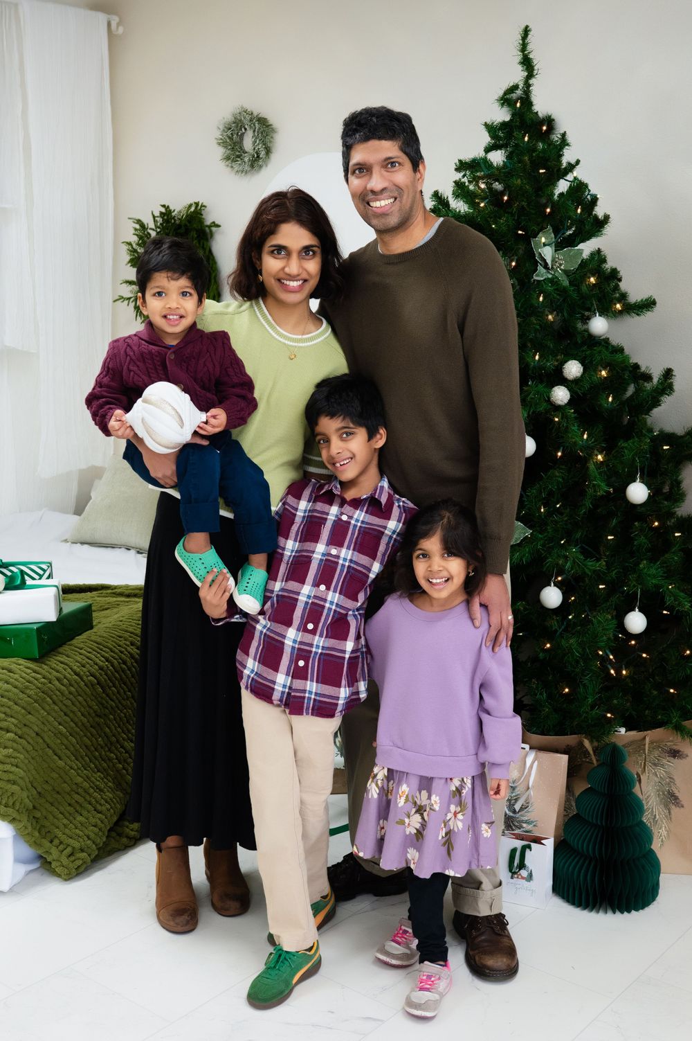 family photo shoot of family of 5 with christmas themed set up at Lume and Sage Photo Studio in Mesquite texas; in front of tree and wreath