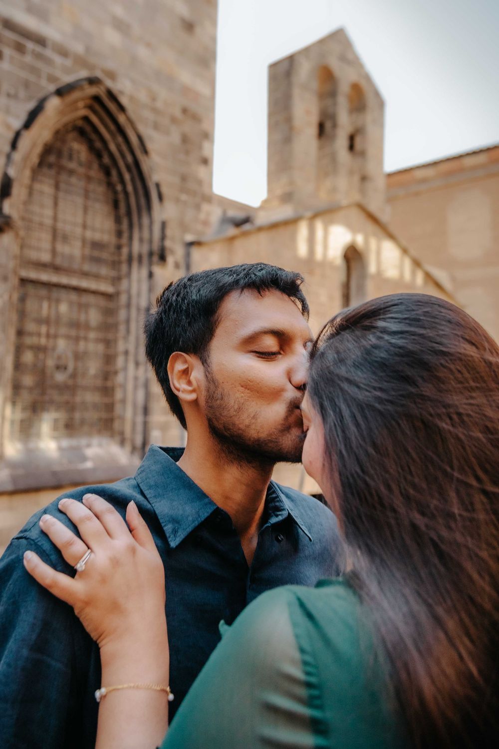 Romantic kiss under a stone archway in El Born district.