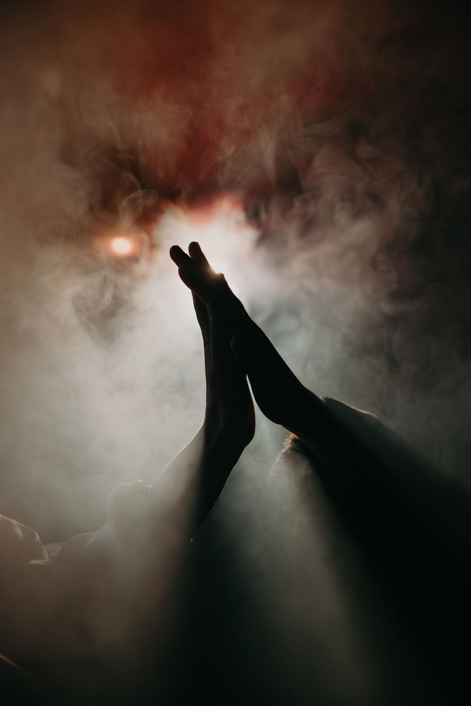 Silhouetted feet against dramatic red and white smoke effects.