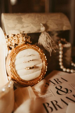 Vintage gold-framed mirror and wedding stationery details captured in warm sepia tones.
