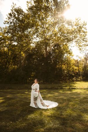 Wedding dress silhouette against golden sunset in grassy field.