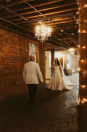A dimly lit brick basement venue decorated with string lights and chandeliers creates a romantic atmosphere.