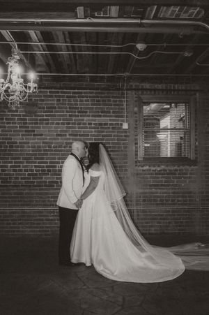 Black and white photos show a couple in formal attire dancing together in a brick-walled venue with chandeliers.