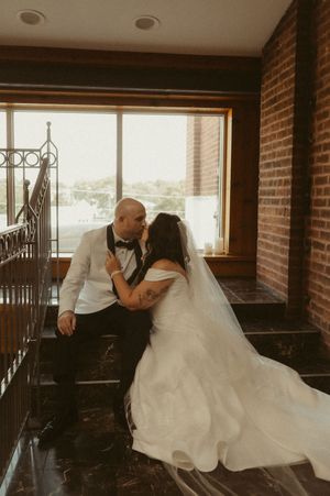 Romantic wedding scene in an industrial brick-walled venue with large windows.