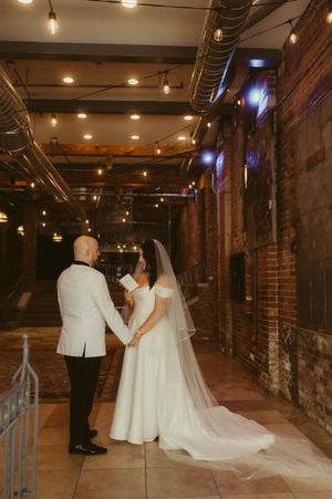 Wedding couple in an industrial-style venue with exposed brick walls and string lights creating ambient lighting.